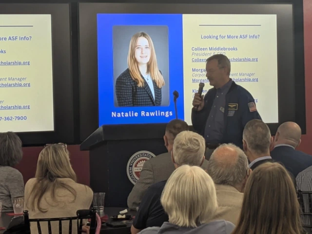 person standing in front of room with microphone introducing student