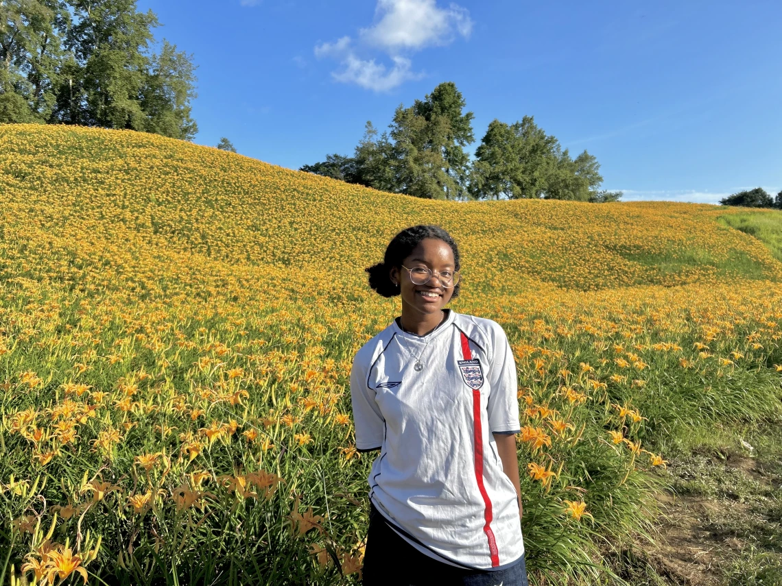 woman standing in front of hillside of yellow flowers
