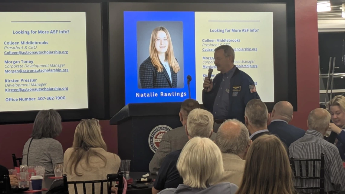 person standing in front of room with microphone introducing student